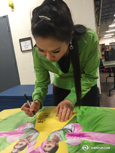 Back in Canada after touring Europe, Shen Yun International Company was busy signing this year’s poster to leave behind as a souvenir. (photo by projectionist Annie Li)