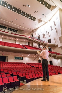Trombonist Alistair Crawford warms up before a soon to be full concert hall.