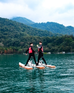 En el Lago de Sol y Luna de Taiwán, los bailarines admiran las plácidas aguas turquesas rodeadas de montañas boscosas.